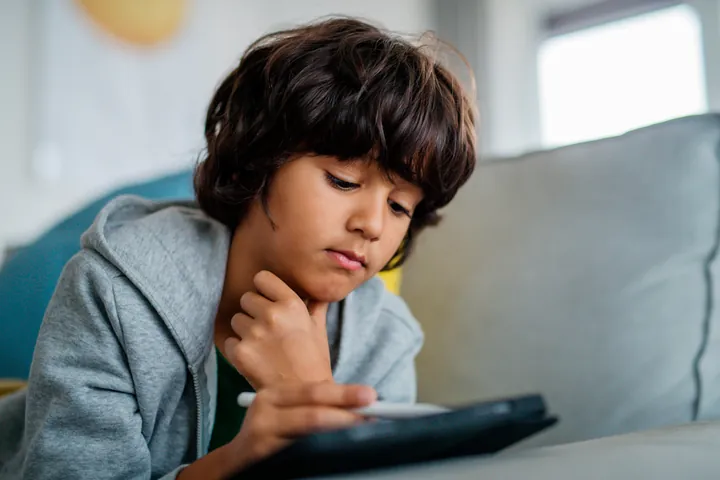 Photo of a child working on his iPad.