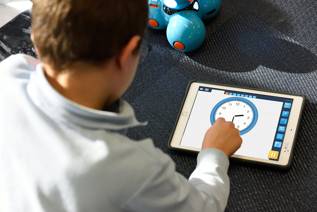 Photo d'un enfant effectuant un exercice sur l'iPad où il déplace les aiguilles d'une horloge.